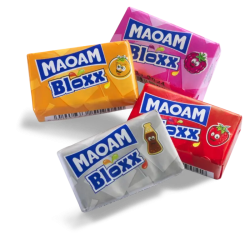 Fyra individuellt förpackade MAOAM Bloxx i smakerna apelsin, hallon, cola och jordgubbe mot vit bakgrund