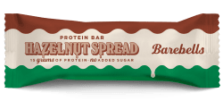 Barebells Hazelnut Spread proteinbar 45g i förpackning med brun, vit och grön design, med synlig chokladfylld bar bredvid
